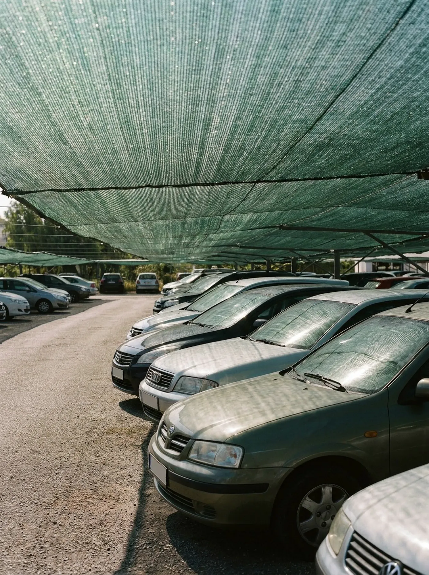 Cars parked under a shade net canopy